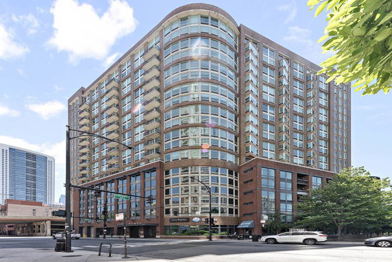 Front view of a multi-story urban building with large windows and corner balconies.