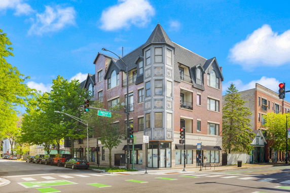 Front view of a multi-story building with a unique corner design and large windows.