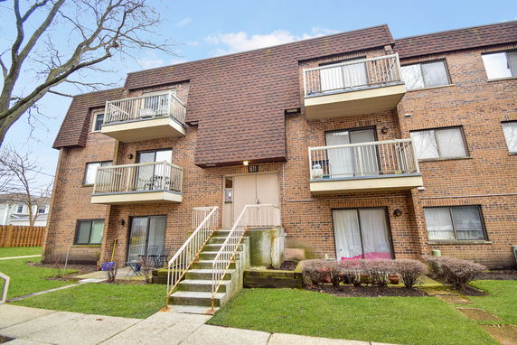Front view of a three-story brick apartment building with balconies.