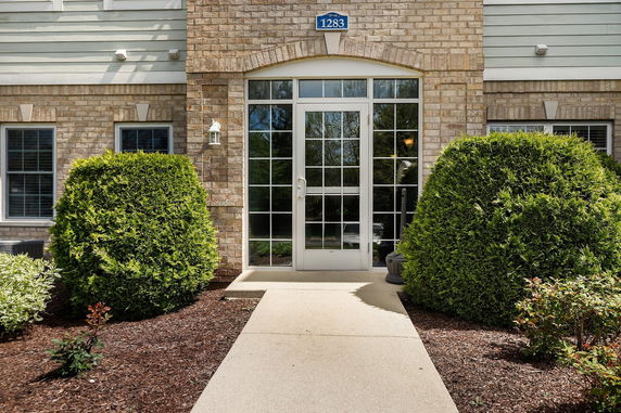 Front view of a building entrance with brick exterior and glass door.