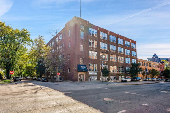 Front view of a multi-story brick building with large windows.