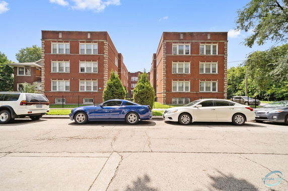 Front view of two adjacent three-story brick apartment buildings with large windows.
