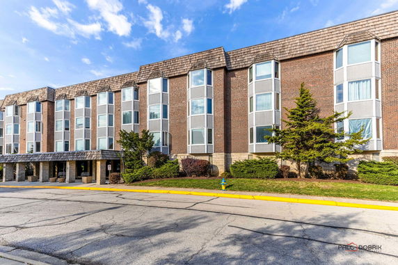Front view of a three-story brick building with large windows and a covered entrance.