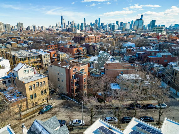 Aerial view of an urban neighborhood with residential buildings and a city skyline in the background.