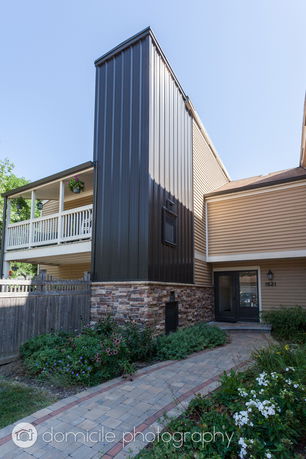 Front view of a modern building with vertical metal siding and stone base.