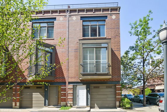 Front view of a three-story brick townhouse with garage and large windows.