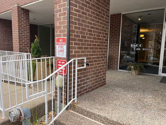 Front view of a brick building entrance with a ramp and glass door.