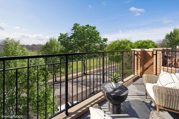 Balcony view overlooking a street and lush green trees.