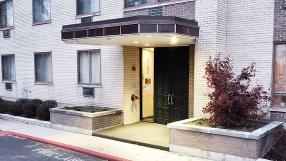 Front view of a multi-story brick building entrance with canopy.
