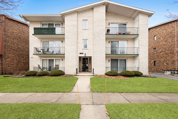 Front view of a three-story apartment building with balconies.