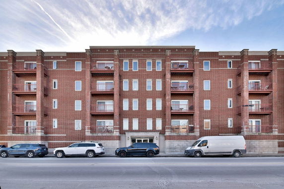 Front view of a multi-story brick apartment building with balconies.