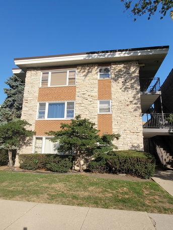 Front view of a three-story residential building with a brick and stone exterior.