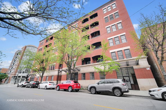 Front view of a multi-story red brick building with large windows.