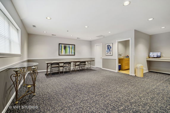 Room with tables, chairs, wall art, and a separate area with a microwave.