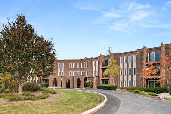 Front view of a brick three-story building with multiple windows and a rounded driveway.