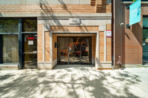 Front view of a building entrance with brown brick exterior and glass doors.