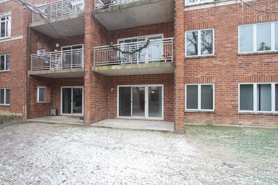 Front view of a multi-story brick building with balconies and sliding glass doors.