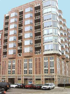 Front view of a multi-story apartment building with brick and glass facade.