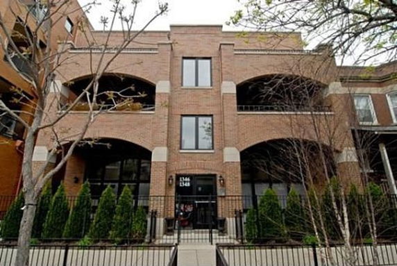 Front view of a three-story brick building with arched balconies and a central entrance.