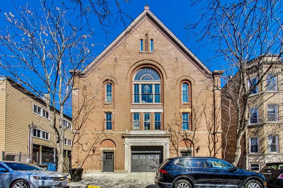 Front view of a multi-story brick building with large arched windows.