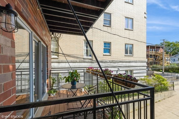 Balcony view of multi-story brick building with nearby structures.
