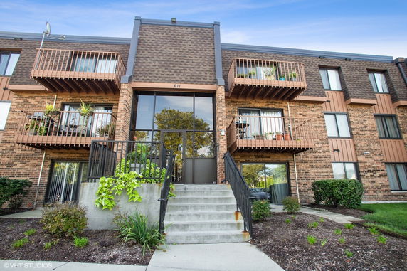 Front view of a multi-story brick building with balconies and a central entrance.