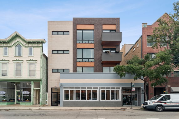 Front view of a multi-story modern building with balconies and large windows.