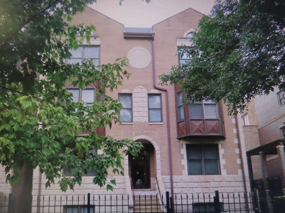 Front view of a brick apartment building with an arched entry.