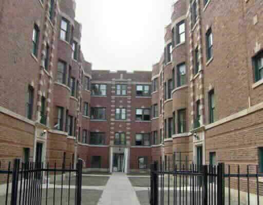 Front view of a multi-story brick building complex with gated entrance.