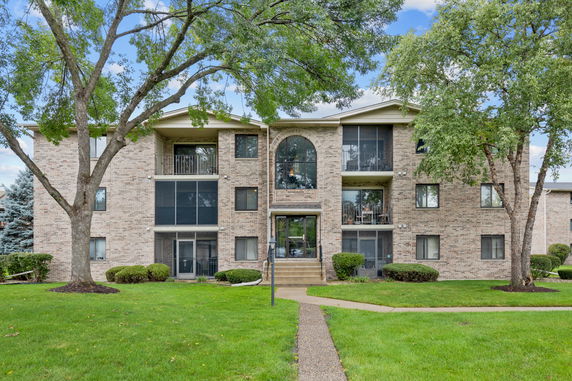 Front view of a multi-story brick building with balconies and a central entrance.