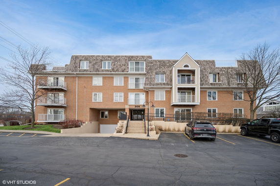 Front view of a multi-story apartment building with balconies and parking area.