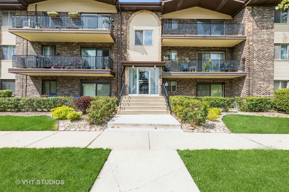 Front view of a multi-story residential building with balconies and entrance steps.
