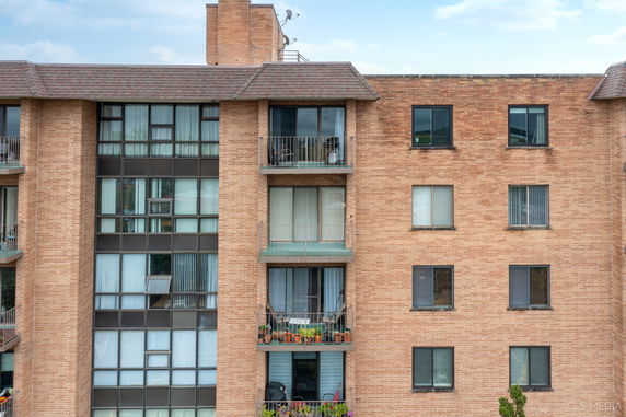 Front view of a multi-story apartment building with balconies and brick exterior.