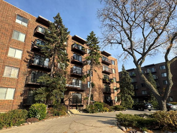 Front view of a multi-story brick apartment building with balconies.
