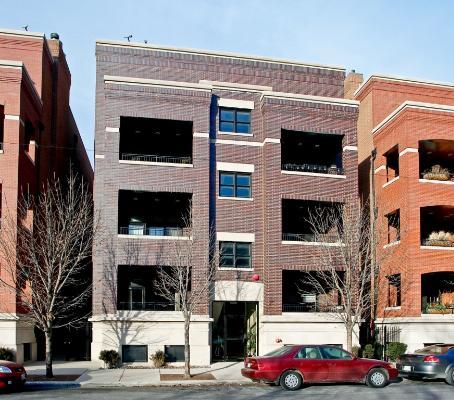 Front view of a multi-story brick apartment building with balconies.