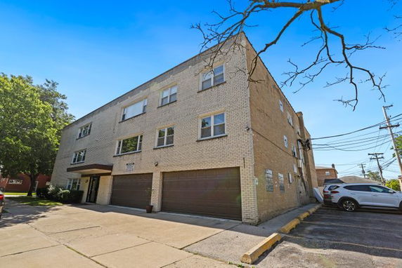 Front view of a three-story brick building with garage openings on the ground level.