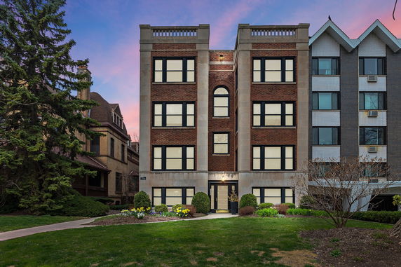 Front view of a four-story brick apartment building with symmetrical windows.