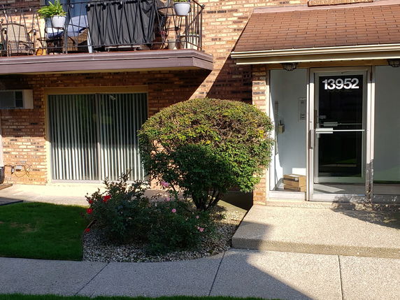 Front view of a brick building with a balcony and a main entrance door.