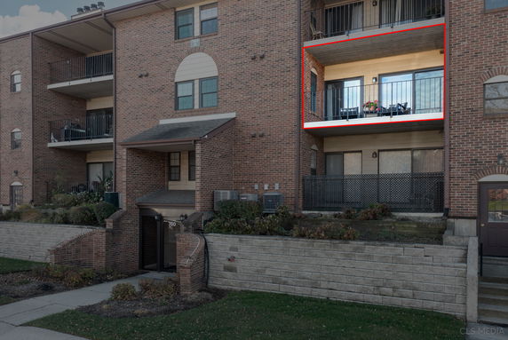 Front view of a multi-story brick apartment building with balconies.