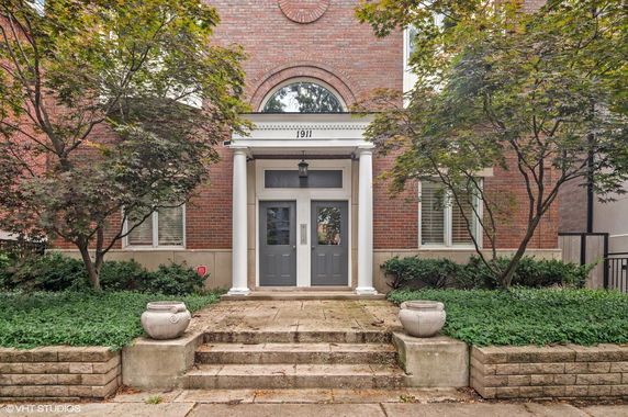 Front view of a brick building entrance with columns and double doors.