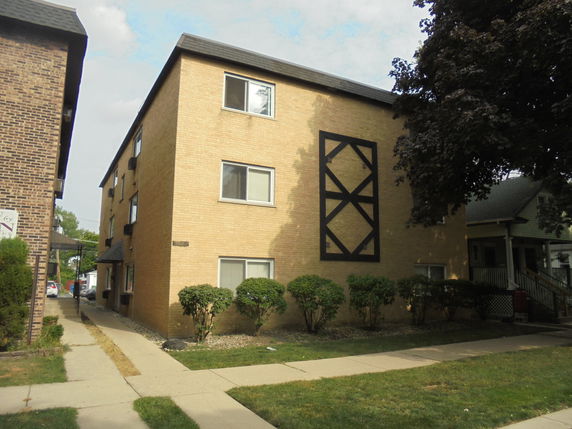 Front view of a three-story brick apartment building with rectangular windows.