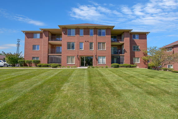 Front view of a three-story brick apartment building with balconies.