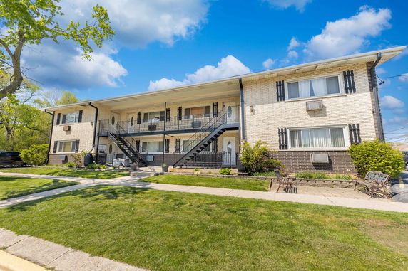 Front view of a two-story apartment building with balconies and stairs.