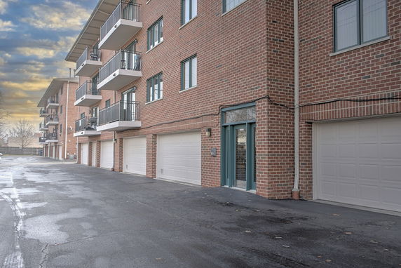 Front view of a multi-story brick building with balconies and garages.