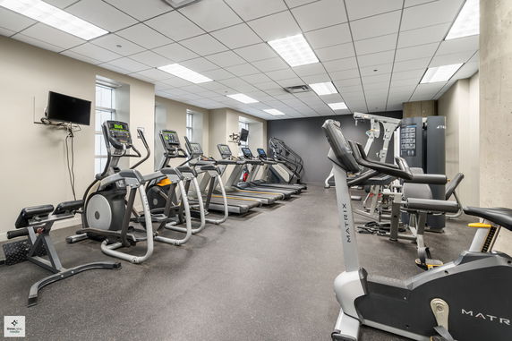 Indoor gym area with exercise equipment including treadmills, elliptical machines, and stationary bikes.