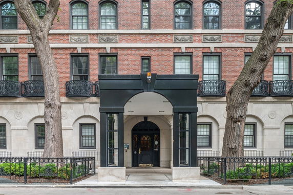 Front view of a brick building with decorative balconies and entryway.
