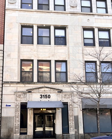 Front view of a multi-story building with decorative facade and windows.