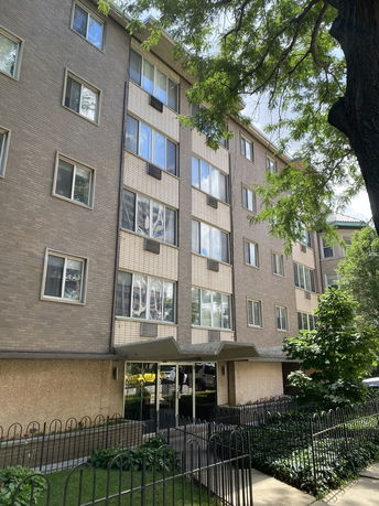 Front view of a multi-story residential building with a gated entrance.