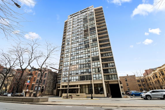 Front view of a high-rise residential building with balconies and glass windows.