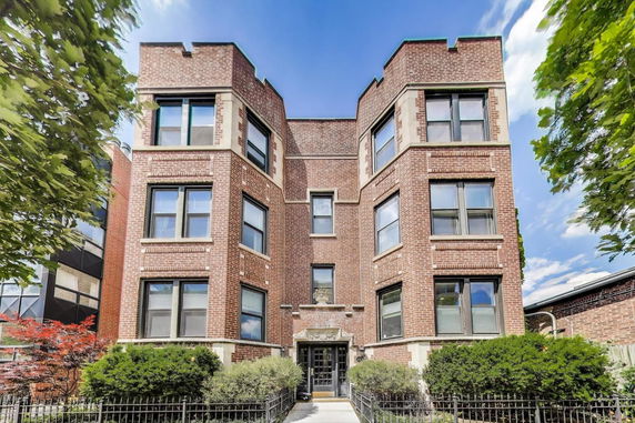 Front view of a multi-story brick building with large windows.